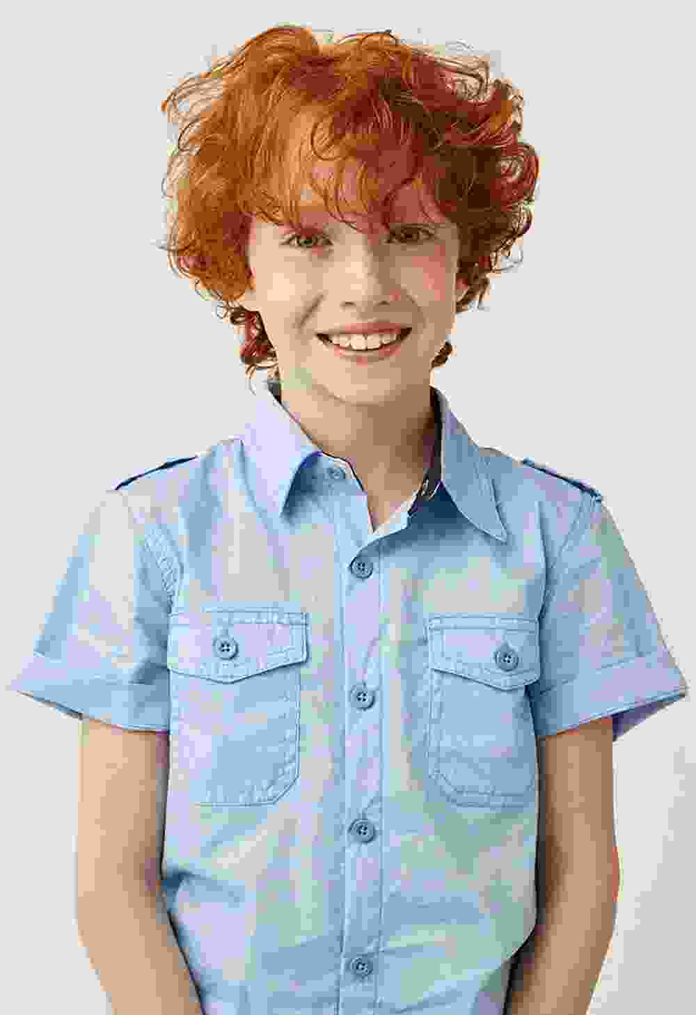Smiling red-haired boy in a light blue short-sleeve shirt.