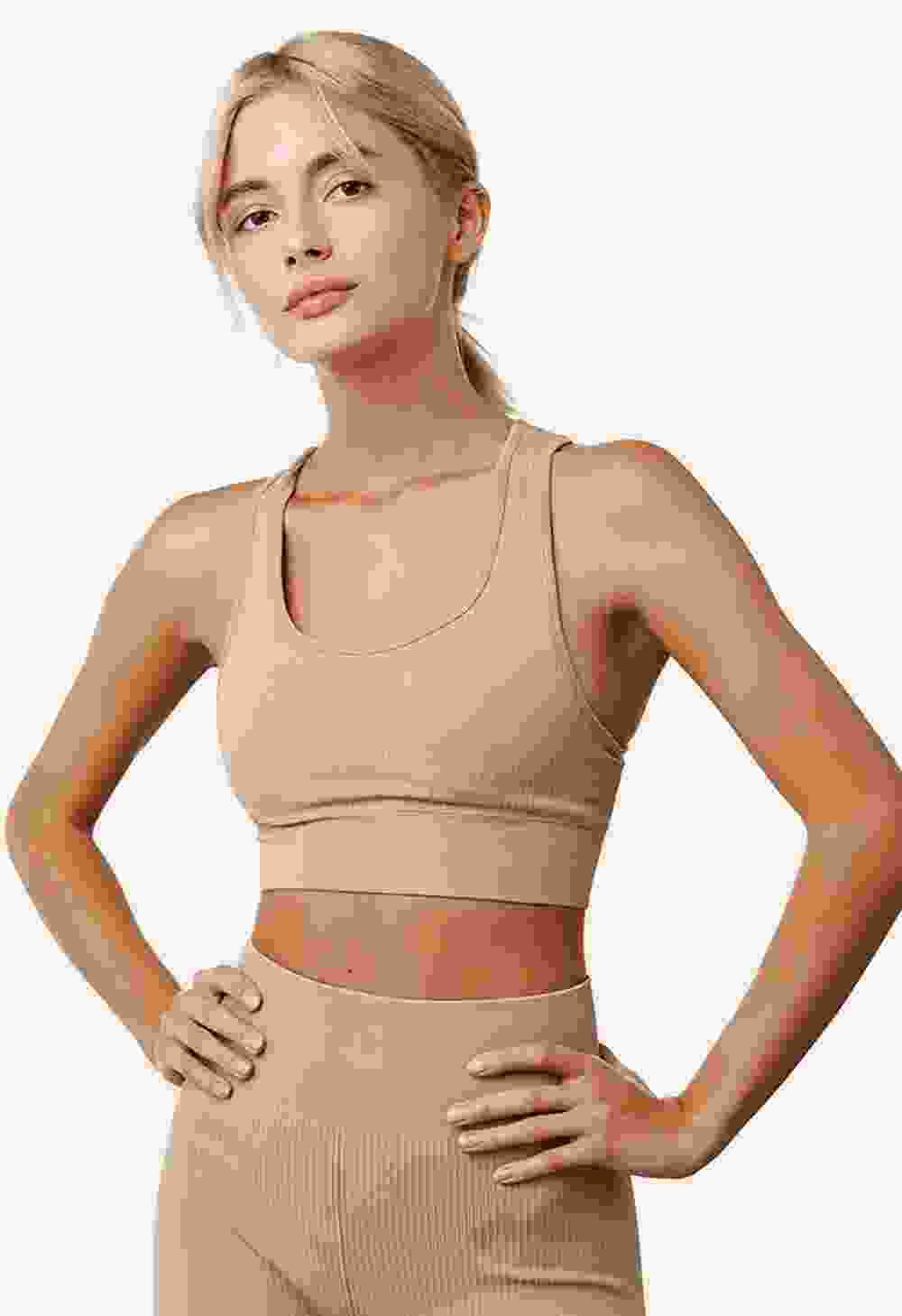 Woman wearing beige athletic wear with hands on hips.