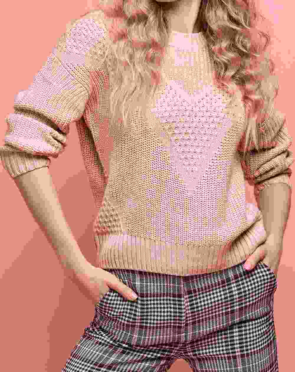 Woman wearing a beige heart-patterned sweater and checkered pants.