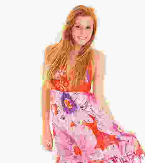 A smiling woman in a colorful floral dress against a white background.