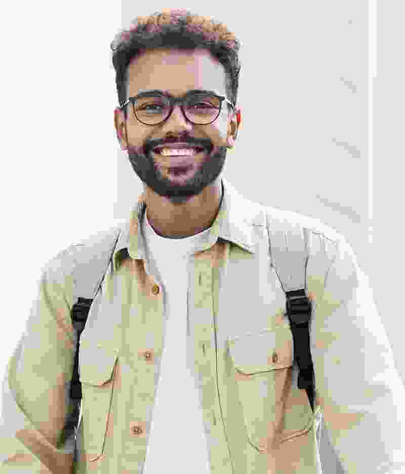 Smiling young man with glasses and a backpack.