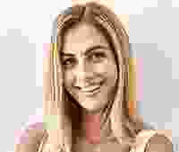 Smiling woman with long blonde hair against a light background.