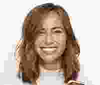 Smiling woman with wavy hair against a plain background.