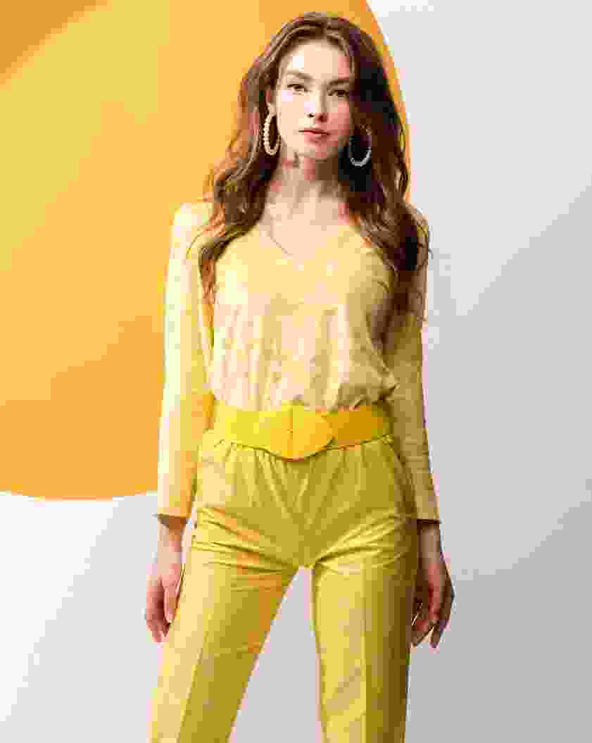 Fashionable woman in a yellow outfit with a wide belt and hoop earrings.