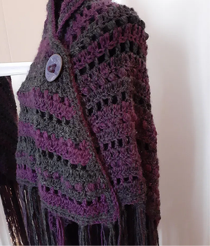 Crocheted shawl with purple and gray stripes and a decorative button.