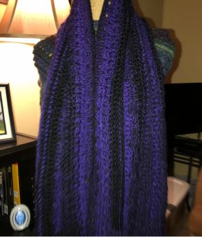 A cozy purple and black knitted scarf draped over a chair.