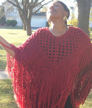 Woman wearing a red fringed poncho outdoors on a sunny day.