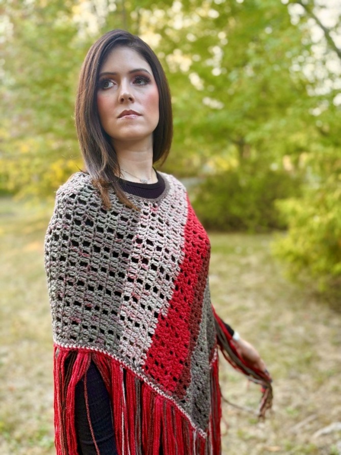Woman outdoors wearing a multicolored crocheted poncho.